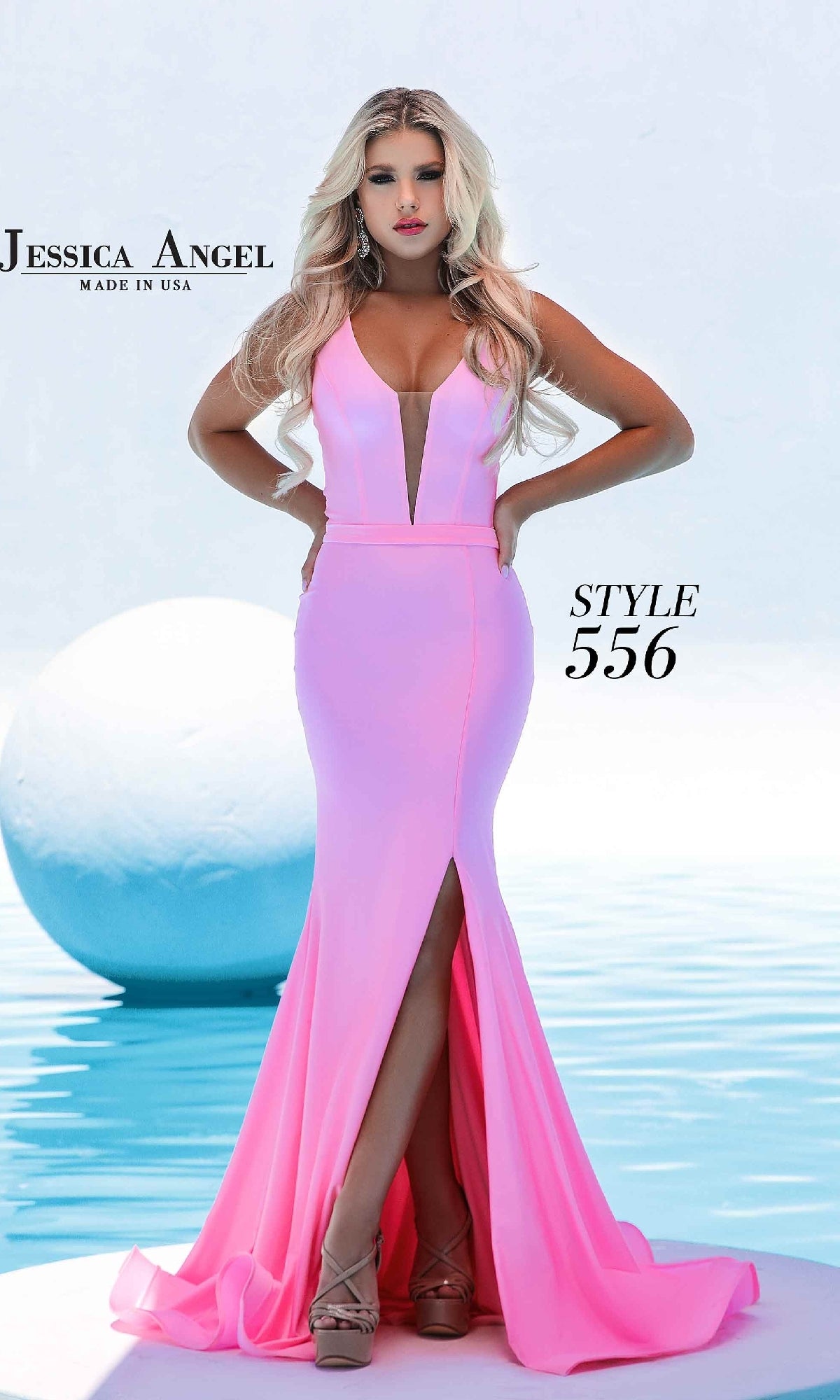 A woman stands by a pool in the Jessica Angel 556, a fitted, floor-length mermaid prom dress featuring a plunging V-neckline and front slit.